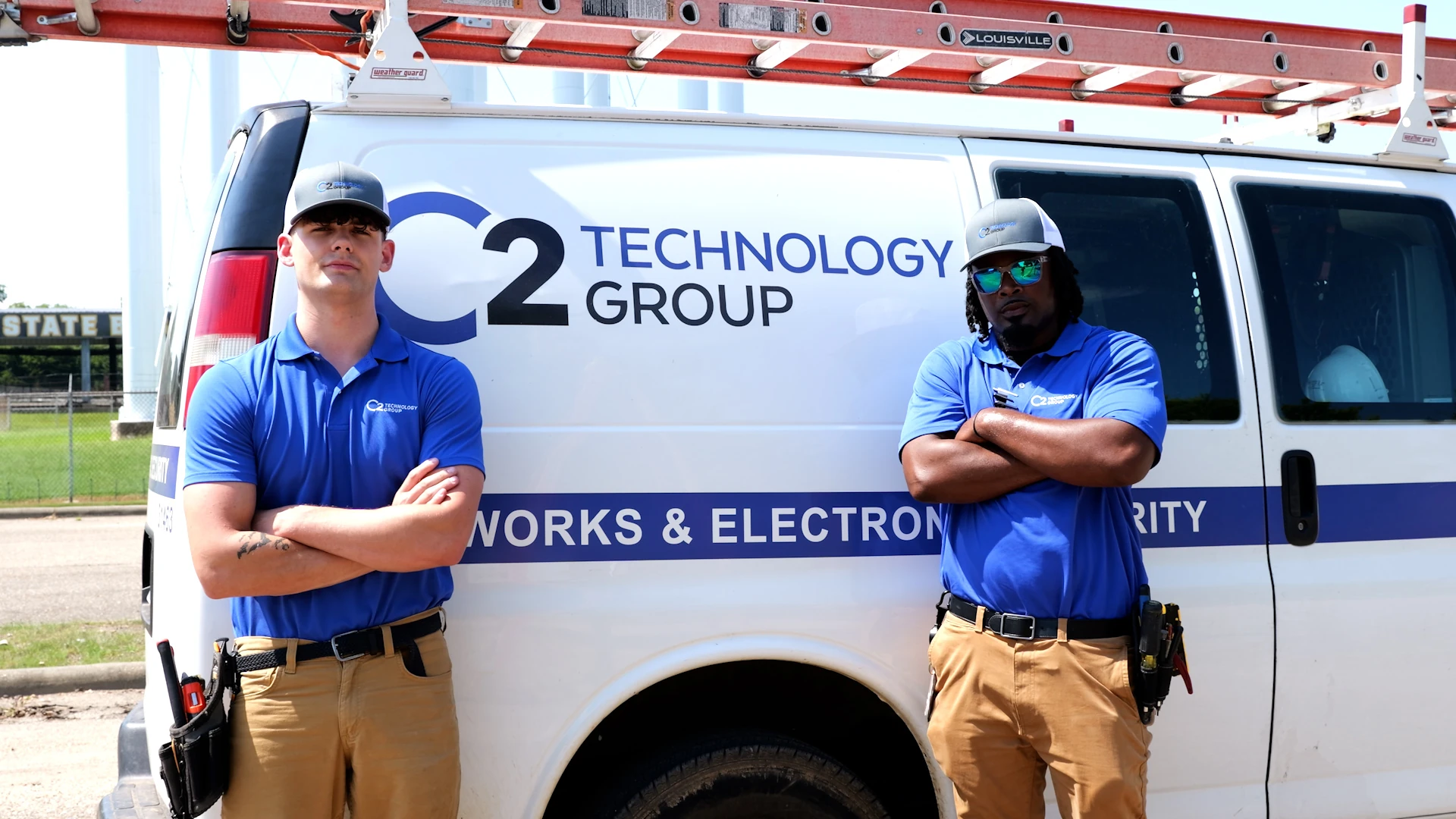 Two C2 Technology Group technicians standing beside their branded service van
