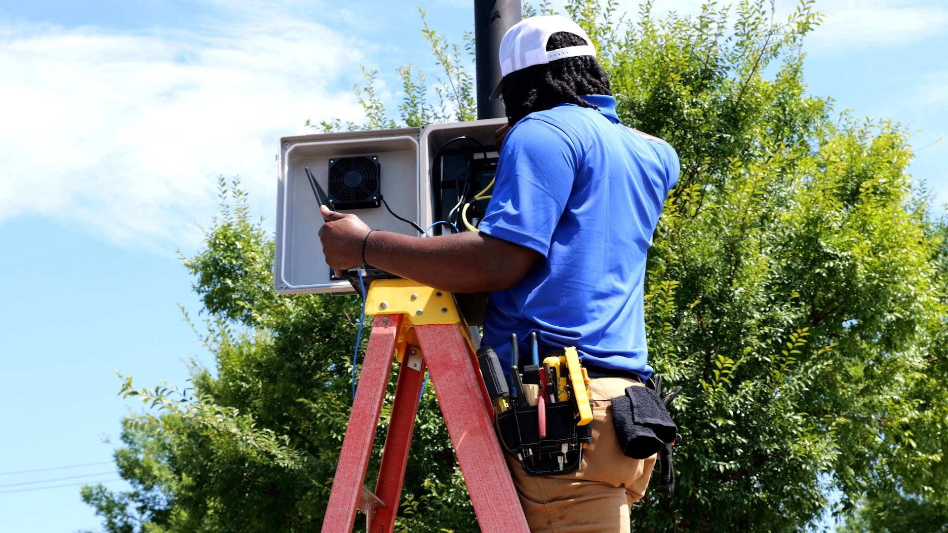 C2 Technology Group technician working on an outdoor network equipment enclosure