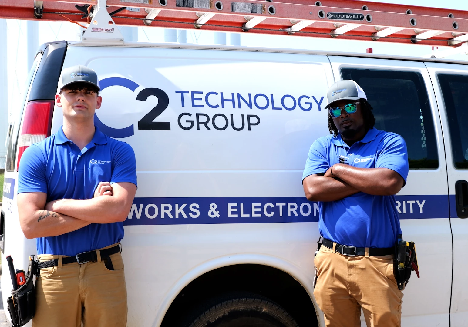 Two C2 Technology Group technicians standing in front of a service van